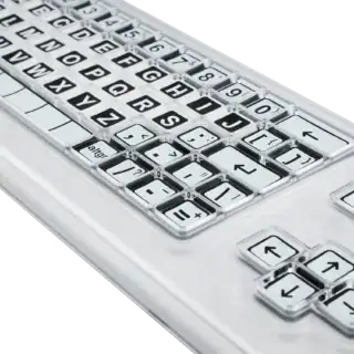 Close up image of a black and white keyboard with a clear perspex keyguard separating the keys.