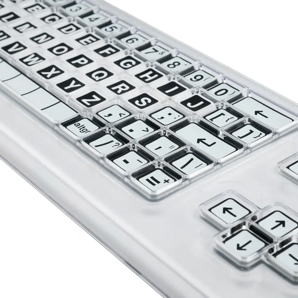Close up image of a black and white keyboard with a clear perspex keyguard separating the keys.