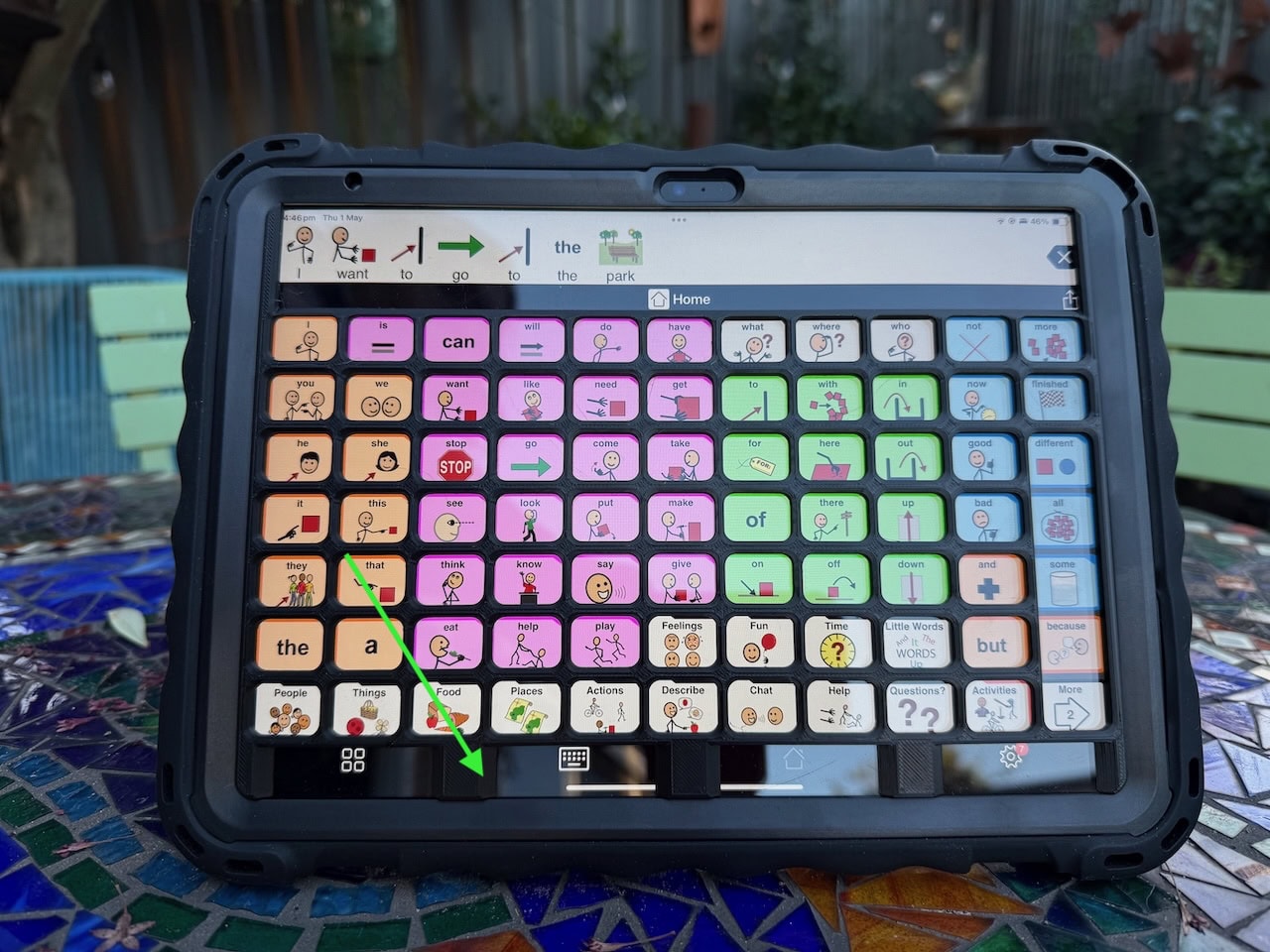 A black keyguard on an iPad with Proloquo2go page set displayed. A green arrow is pointing to the customisation of the keyguard at the bottom, with the 4 menu options displayed instead of 5.