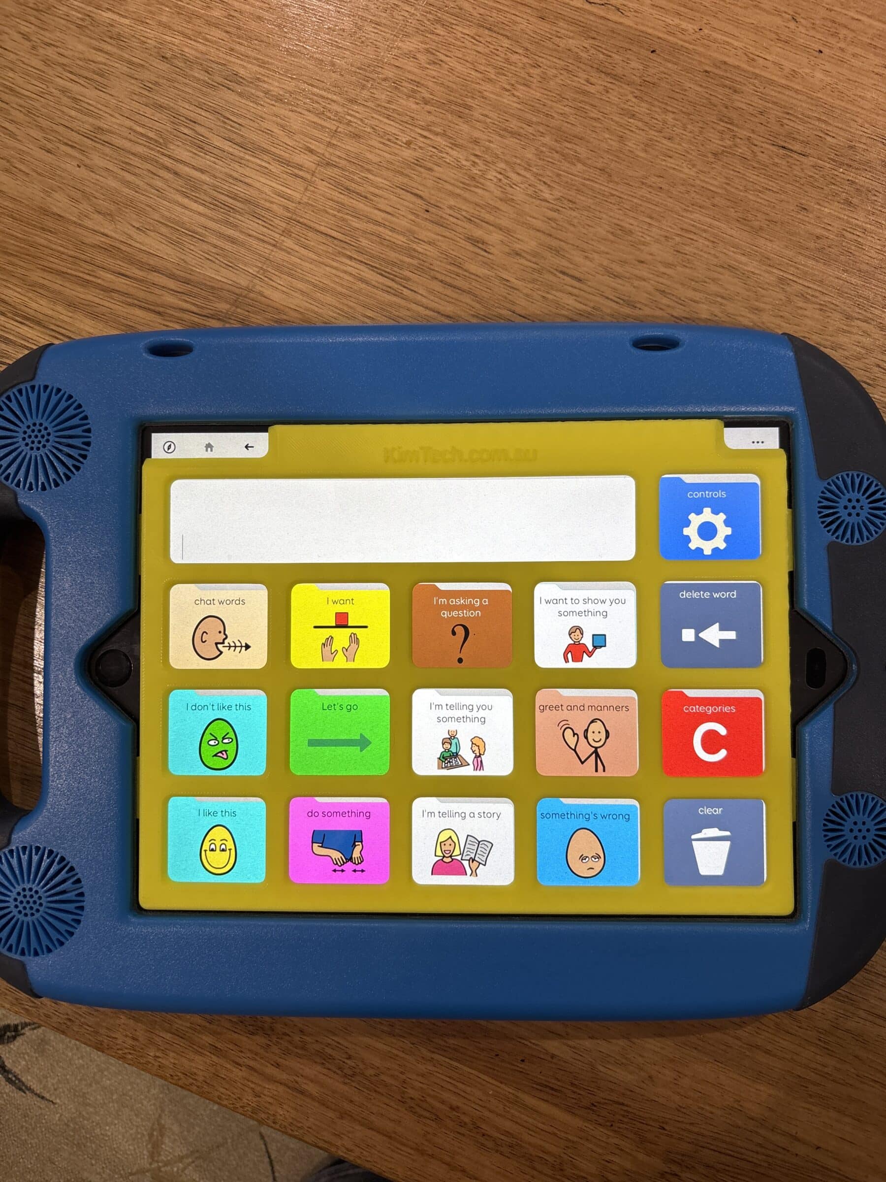 A yellow keyguard on on iPad in a GoNow case. The app displayed on the iPad is PODD 15.